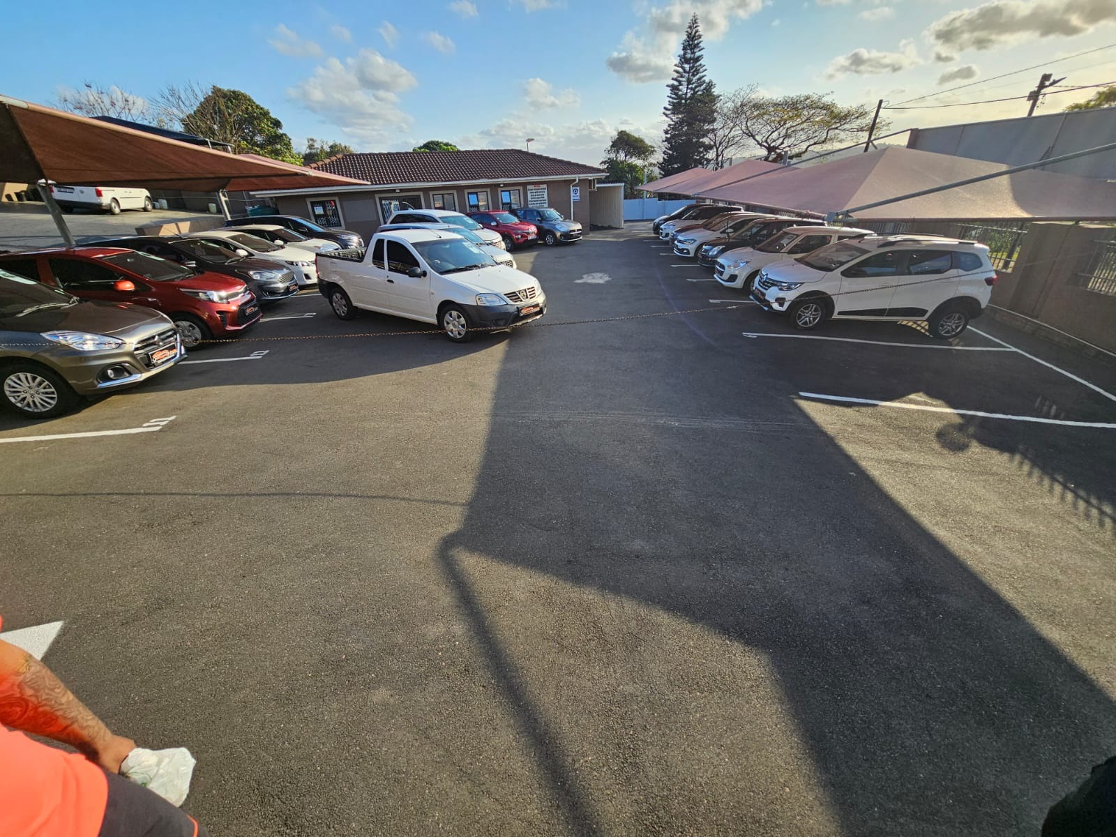 A sleek, luxury car showroom displaying a lineup of premium vehicles under soft diffused lighting. The showroom features polished marble floors, creating a reflective surface that enhances the elegance of the cars. The color palette includes deep blues and shiny silvers, evoking a feeling of sophistication. Shot from a low angle perspective, the viewer's gaze is drawn upwards towards the gleaming cars. Each car is adorned with detailed textures, showcasing glossy paint and intricate design lines. Elegant chandeliers hang from the ceiling, providing warm light that complements the overall ambiance. Background elements include stylish plant arrangements and a modern reception area. The image is in the style of famous automotive photographers, emphasizing hyperrealism. Render in 8K resolution, capturing every minute detail in ultra-high quality.